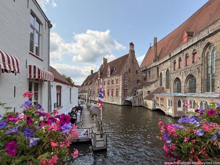 Tourists on a guided canal boat tour through the historic waterways of Bruges, Belgium, passing under stone bridges
