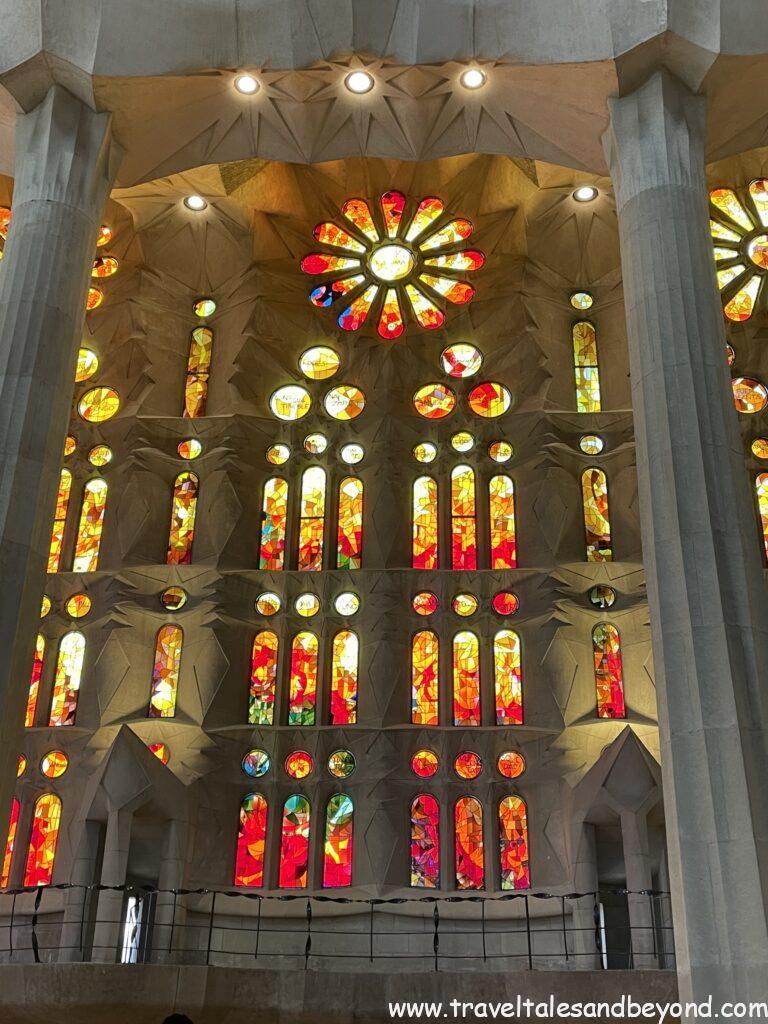 Warm red and orange stained glass windows flooding light into the interior nave of Sagrada Família basilica, Barcelona, Spain