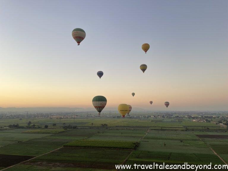 Hot air balloons over the green fields by the Nile river